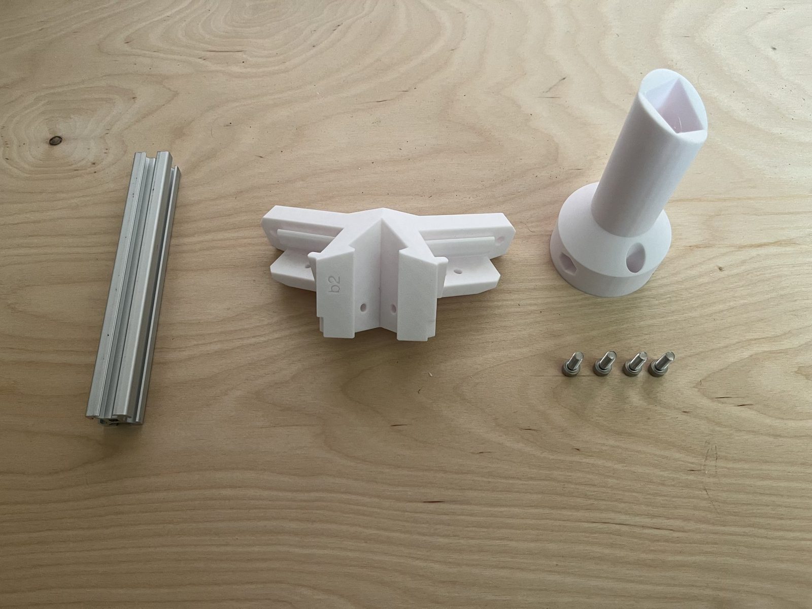 Side bracket, bottom-vertical leg, cover, an extrusion offcut, and the four M5 × 16 mm screws laid out before assembly